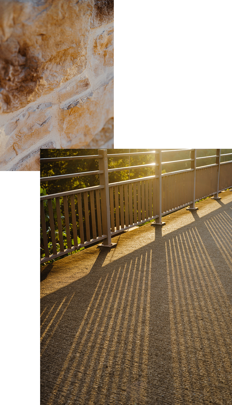 Warm stone wall and sunlit walkway railing casting shadows at The Lanes Nashville wellness community.