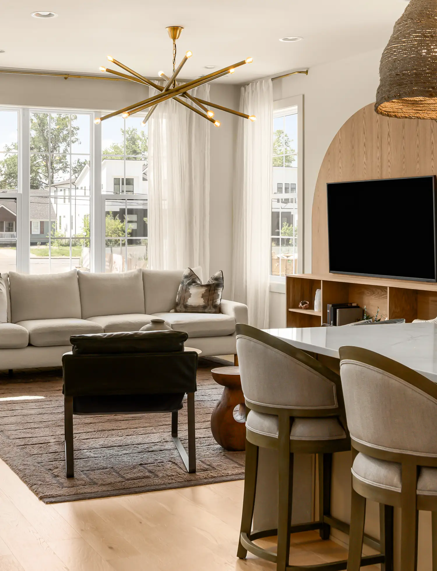 solaya-homes-murphy-maude-living-room-b Living room with a brass chandelier and kitchen island seating in a home at Solaya at the Lanes